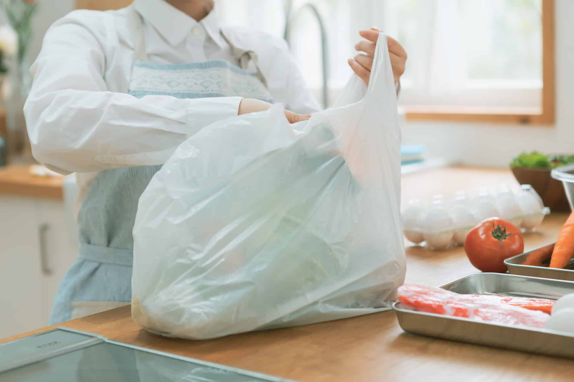 ビニール袋から食品を取り出す主婦